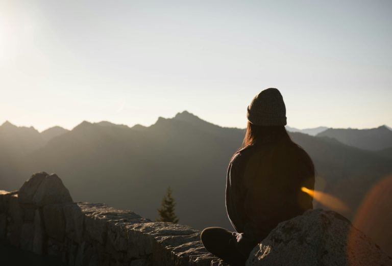 Person sitting on wall, watching mountain sunset