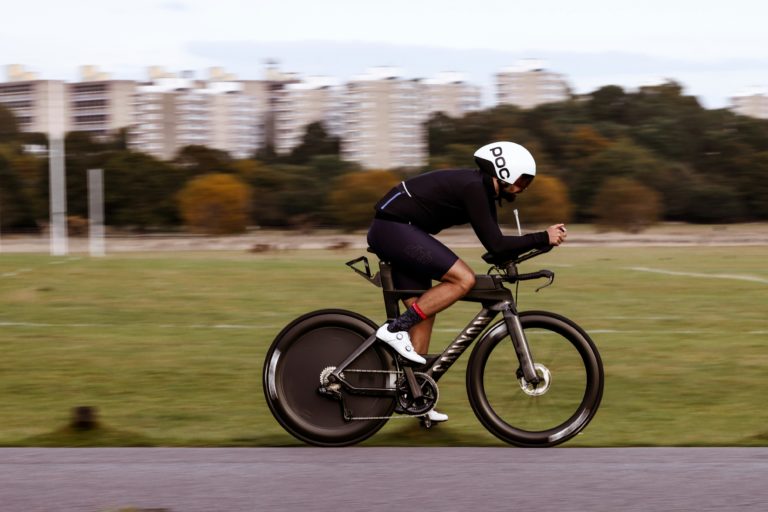 Cyclist riding fast on black bicycle in city park.