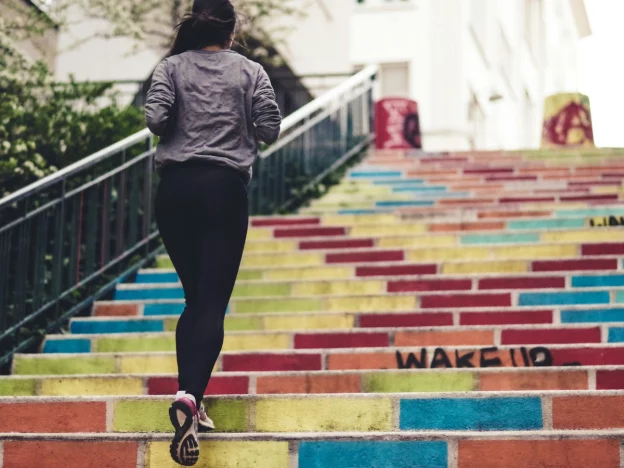 Woman jogging up colorful stairs outdoors.