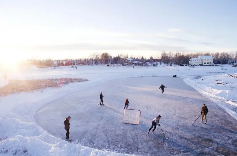 People playing hockey on frozen outdoor pond.