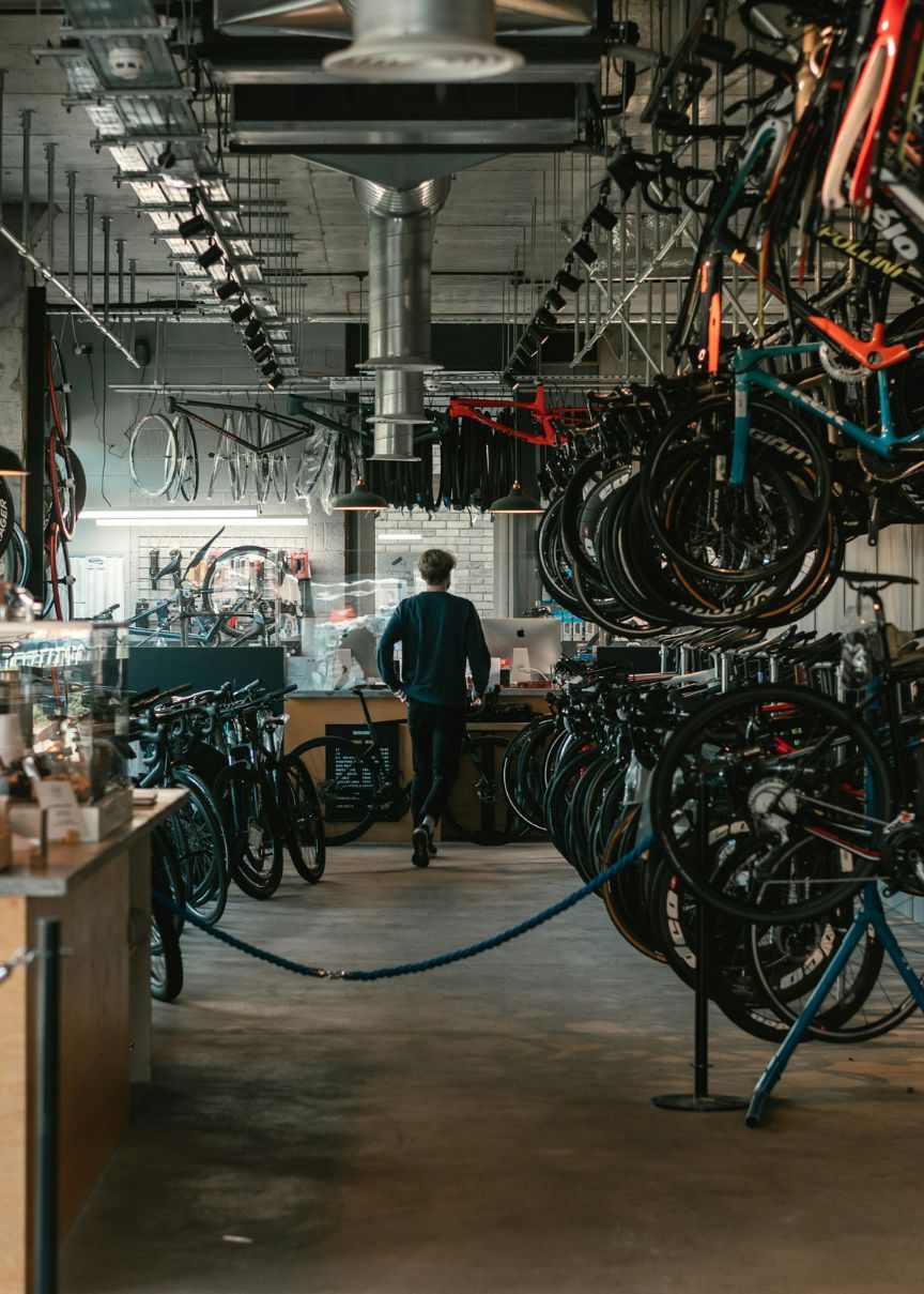 Person in bicycle shop, surrounded by bikes.